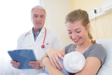 Obraz premium new mum with baby talking to doctor and smiling