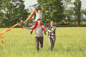 Happy family flying kite in the field