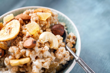 Bowl with tasty oatmeal and spoon on table