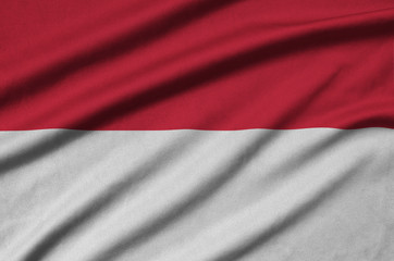 Monaco flag  is depicted on a sports cloth fabric with many folds. Sport team banner