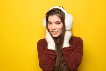 Beautiful young woman in warm clothes on color background