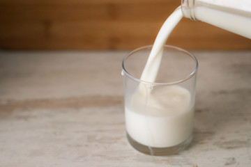 Milk pouring in glass from bottle. Copy Space.