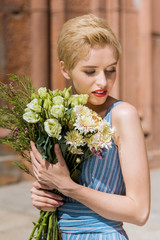 attractive girl in trendy dress holding bouquet of flowers
