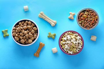 Bowls with pet food on color background
