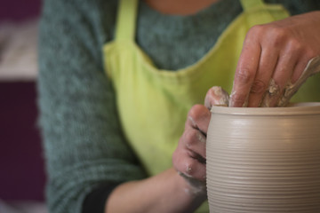potter's hands making a clay pot on pottery
