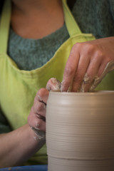 potter's hands making a clay pot on pottery