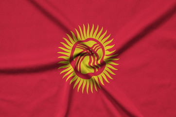 Kyrgyzstan flag  is depicted on a sports cloth fabric with many folds. Sport team banner