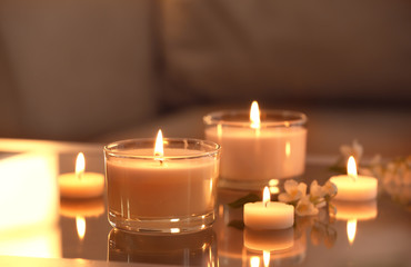 Fototapeta na wymiar Burning candles on glass table indoors