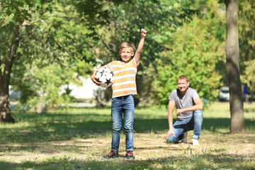 Fototapeta premium Happy father and son playing football in park