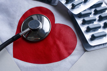 Stethoscope and a few blisters of pills with red heart