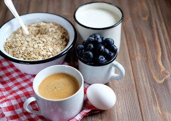A healthy breakfast is a great start to a new day. Oatmeal porridge, coffee, berries and nuts on a wooden table.