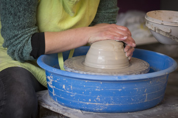 potter's hands making a clay pot on pottery