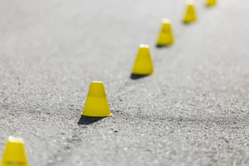 Cones for slalom on roller skates stand on asphalt, inline