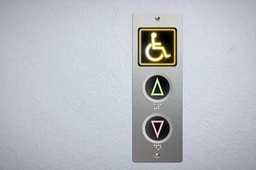 Elevator buttons panel with an amber glowing light button for handicap and Braille code for the...