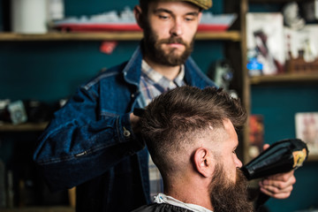 Hipster bearded client getting hairstyle. Styling concept. Barber with hairdryer drying and styling...