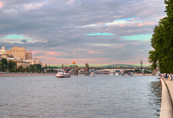 Obraz premium people walk along the Pushkinskaya embankment of Gorky Park against the background of the Moscow River and Andreevsky bridge, Moscow,Russia