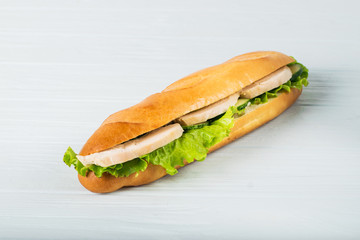 Fresh submarine sandwich with ham, cheese, tomatoes, cucumbers, lettuce and onions isolated on white background