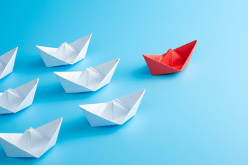 Leadership concept. Red leader paper ship leading among white on blue background.