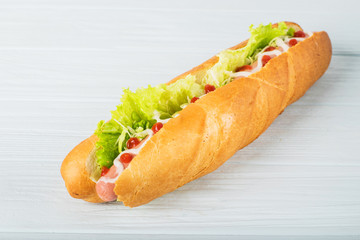 Fresh submarine sandwich with ham, cheese, tomatoes, cucumbers, lettuce and onions isolated on white background