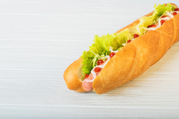 Fresh submarine sandwich with ham, cheese, tomatoes, cucumbers, lettuce and onions isolated on white background