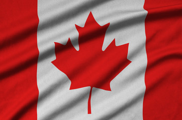 Fototapeta premium Canada flag is depicted on a sports cloth fabric with many folds. Sport team banner