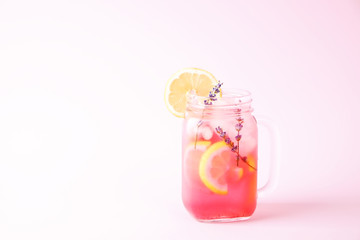 Red berry lavander lemonade, lemon and straw. Virgin strawberry mojito, non alcoholic cocktail with ice in vintage mason jar glass, Isolated on pale pink background. Copy space, top view, close up.