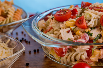 Delicious pasta salad or Mediterranean salad. Tomatoes mozzarella basil corn spice and olive oil on a wooden table. Traditional Italian food