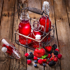 Drink Summer from Mix Berries Decorated with Green Mint. Compote in Glass Bottles. Old Wooden...