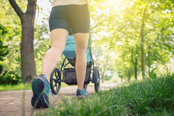 Walking woman with baby stroller enjoying summer in park - 210203219