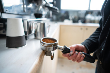 Barista holding portafilter with ground coffee