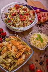 Delicious pasta salad or Mediterranean salad. Tomatoes mozzarella basil corn spice and olive oil on a wooden table. Traditional Italian food