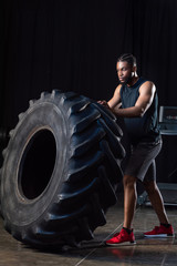 Fototapeta na wymiar full length view of athletic african american man training with tyre and looking away
