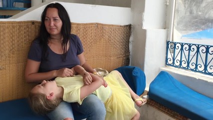 Young woman mother stroking sick stomach daughter lying on her lap