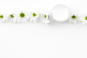 Fototapeta na wymiar Chamomile cream. Face and body care. Cosmetics in small jar near chamomile flowers on white background top view copy space