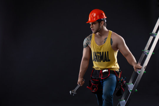 Portrait of handsome builder with construction ladder on black background - Powered by Adobe