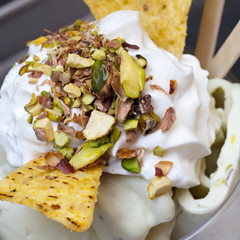 Roll ice cream is made by hand on the freezer. Sweet dessert made with potato chips and ground nuts of pistachios.