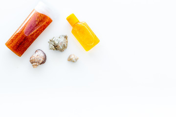 Sunscreen for sea vacation. Bottles with cream or lotion near sea shells on white background top view copy space
