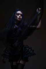 Woman with red hair and black veil posing on dark background