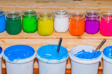 colorful of Plastisol Ink in the clear glass can on the pinewood table for screen print tee shirt....