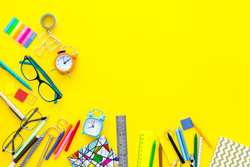 Education concept. Stationery frame with glasses and notebook on yellow background top view copy space