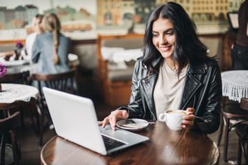 Young pretty spanish woman in cafe in city centre with tablet laptop