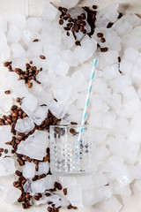 Coffe cocktail frappe making concept. cocktail glass with tube with roasted coffee beans over crushed ice cubes. Flat lay, space.