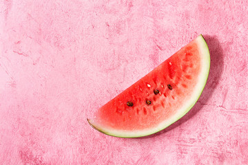 Fototapeta na wymiar Ripe slice of watermelon over pink texture background. Flat lay, space.