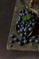 Fresh juicy blueberries on a vintage metal scoop. Close-up, selective focus, low key.