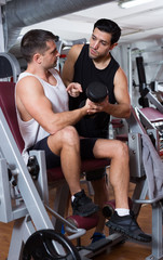 Man during training with  instructor in gym