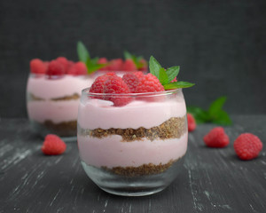 Sweet raspberry mousse in glass bowl on dark background
