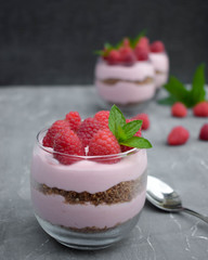 Sweet raspberry mousse in glass bowl on dark background
