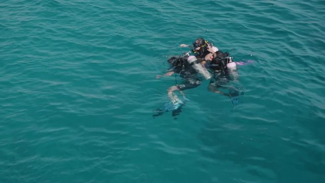 Unidentified scuba divers are preparing for scuba diving. Check inventory. They are concerned about the appearance of sharks. Slow motion.