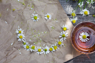 smile of chamomile flowers and herbal tea on a wooden table