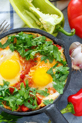 Shakshuka. Frying pan with eggs in tomato sauce.